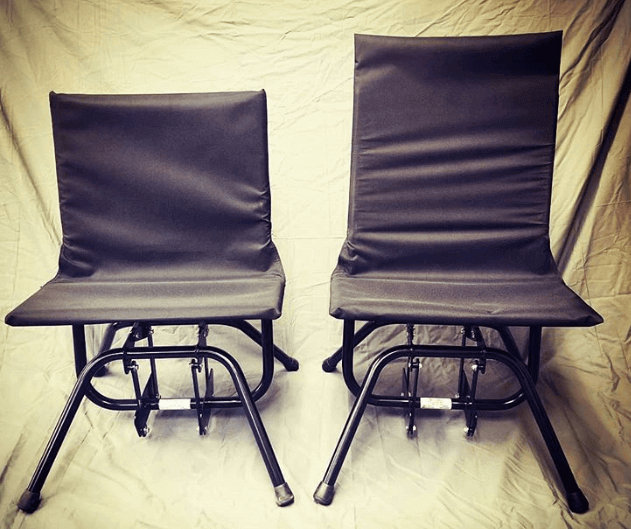 Two black low-slung sex chairs with steel frames and backs on a white background. The chair on the right, which has a slightly higher back, is the Intimate Rider High Back